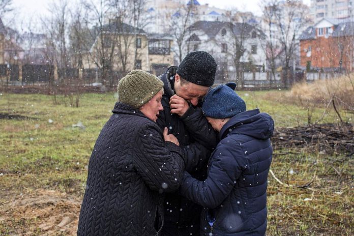 Rodzinna opłakujący krewnych przy masowym grobie w Buczy. Foto: PAP/Abaca