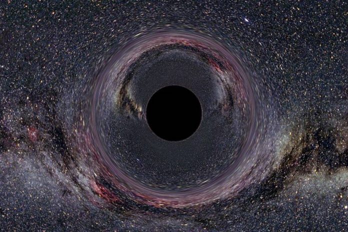 Symulacja czarnej dziury, o masie 10 słońc widzianej z odległości 600 km z Drogą Mleczną w tle. Źródło: wikimedia/ Galerie von Tempolimit Lichtgeschwindigkeit