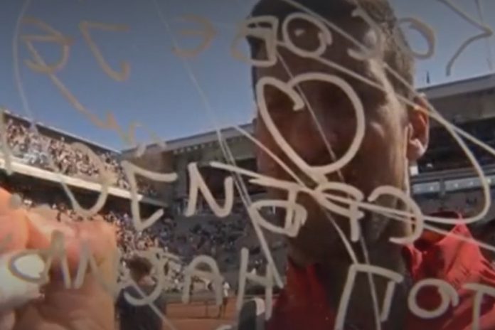 Djokovic piszący markerem na obiektywie kamery 