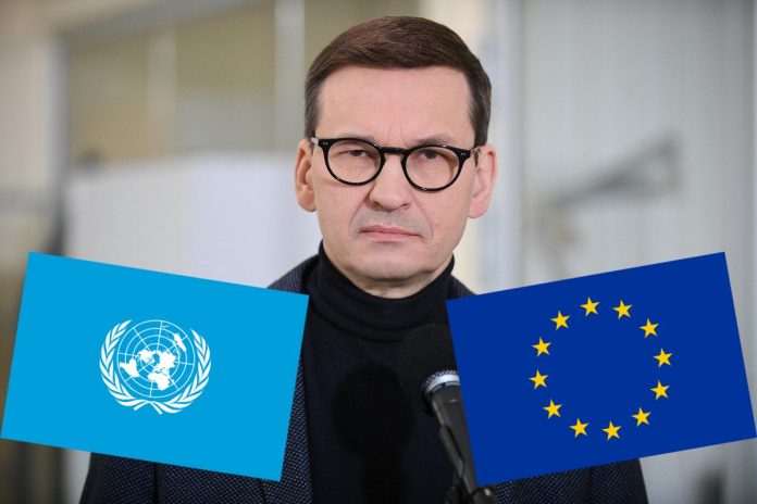Mateusz Morawiecki oraz flagi ONZ i UE.