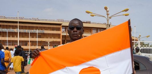 Mężczyzna pokazuje flagę Nigru w drodze na stadion w Niamey, gdzie odbył się wiec poparcia dla junty.